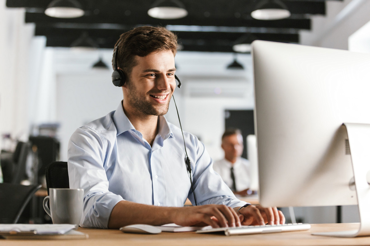 Smiling Male Customer Service Rep on Headset in Front of Computer