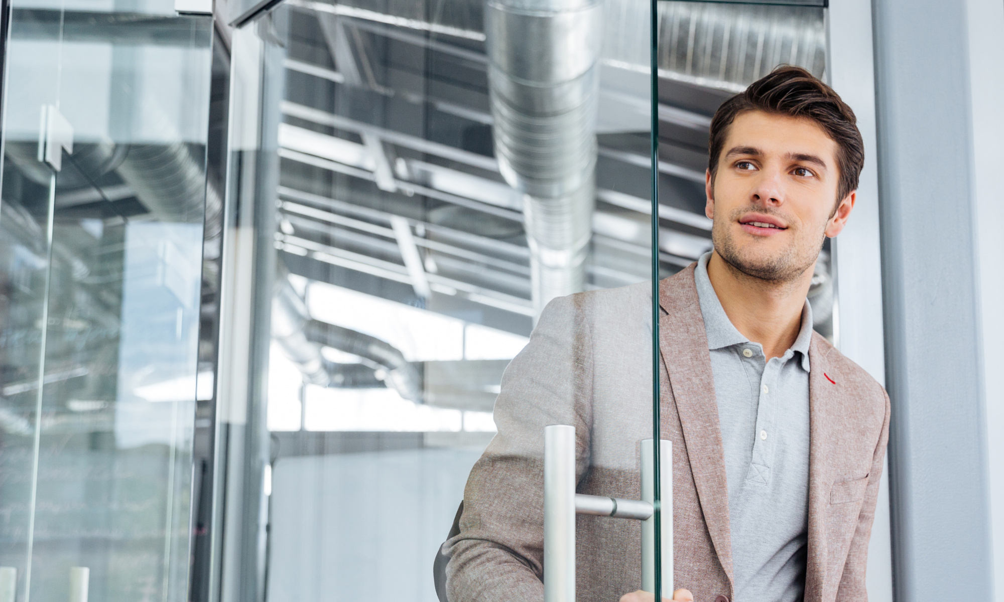 Handsome young businessman with clipboard entering the door in office