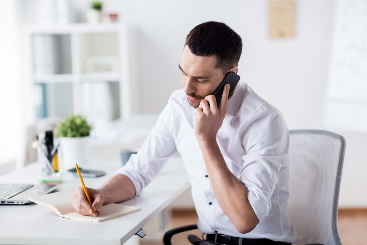 Man Seated at Home Office Desk on Phone
