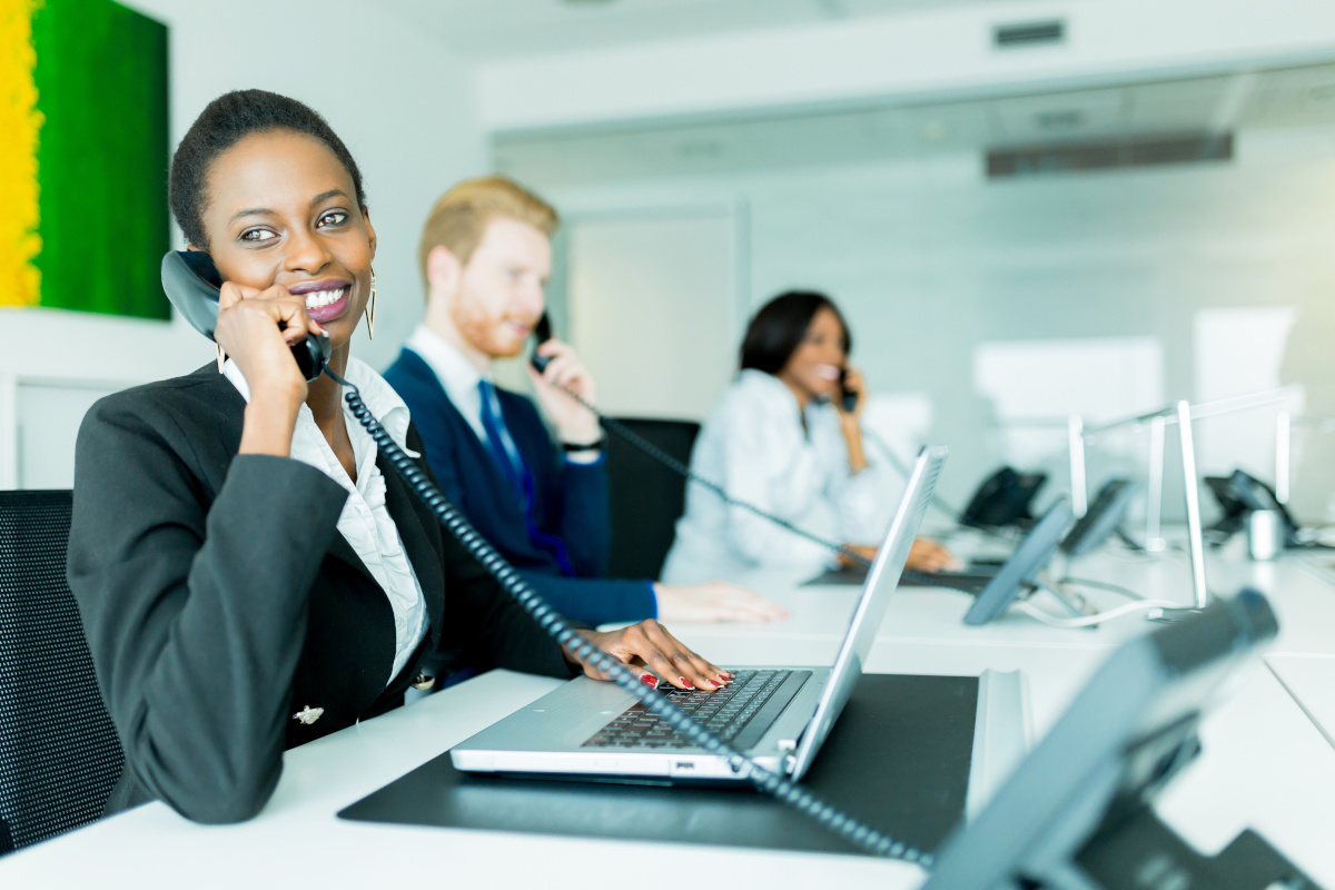 People at work stations answering their desk phones