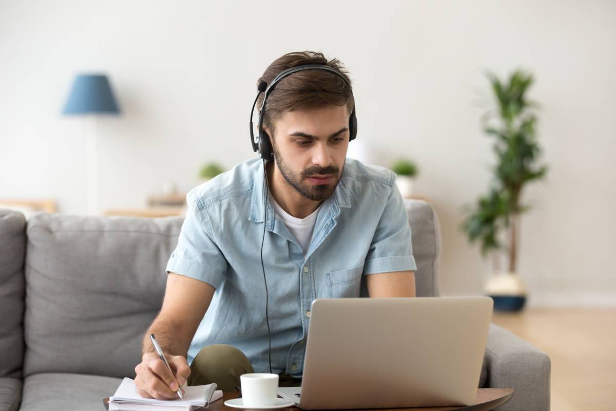 young-man-at-home-on-laptop-wearing-headset-taking-notes-home-office