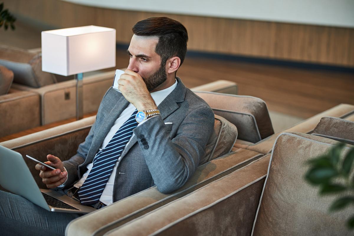 Businessman drinking coffee and using laptop on a comfortable chair