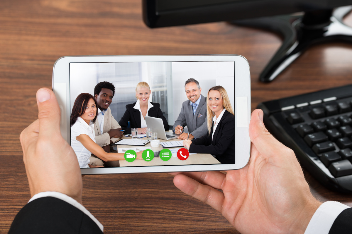 A person holding a mobile phone with a video conference including other coworkers