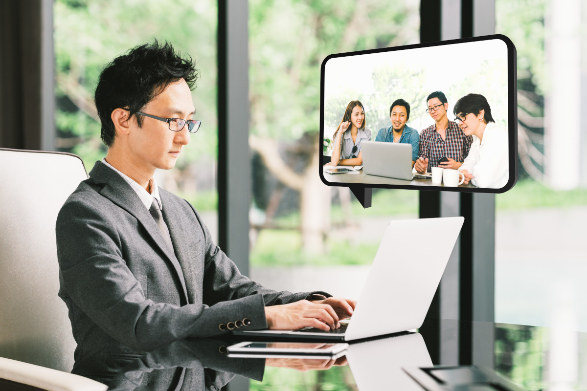 A man working from home and using video conferencing technology to communicate with his co-workers.