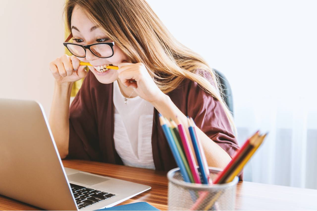 frustrated woman at computer biting a pencil